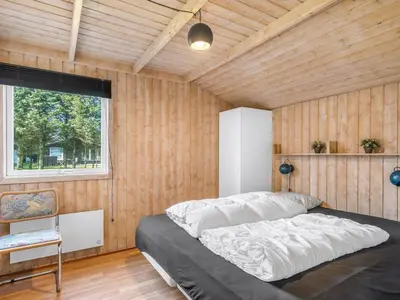 a bedroom with a bed in a room with wooden walls at Holiday Home Peder - 700m from the sea by Interhome in Løkken