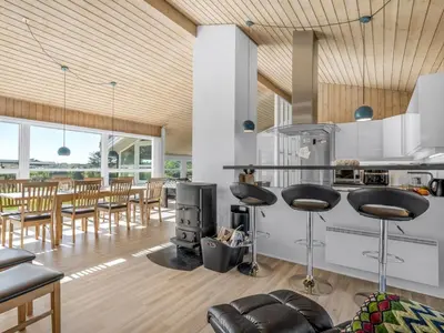 a kitchen and dining room with a stove and chairs at Holiday Home Peder - 700m from the sea by Interhome in Løkken