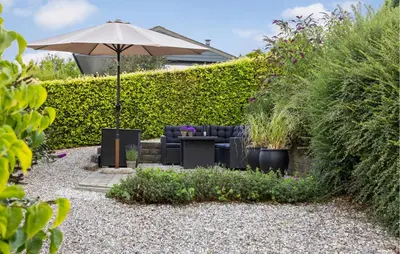 a garden with a couch and an umbrella at 2 Bedroom Cozy Home In Roslev in Roslev