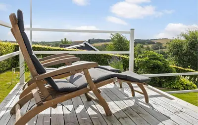 a wooden rocking chair sitting on a wooden deck at 2 Bedroom Cozy Home In Roslev in Roslev