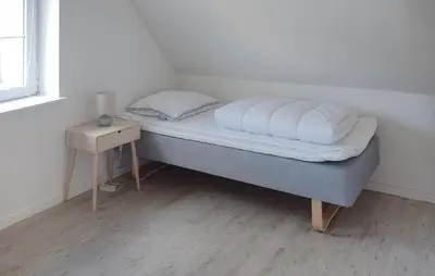 a small bed with white sheets and a night stand at 4 Bedroom Beautiful Home In Farsø in Farsø