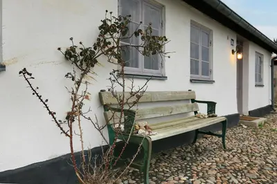 a bench sitting in front of a house at Historic Ferry House By Limfjorden In Sillerslev in Øster Assels