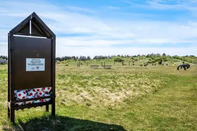 a sign in a field with horses in the distance at JB374-Brovst-Kronvildtvej-222 in Tranum Strand
