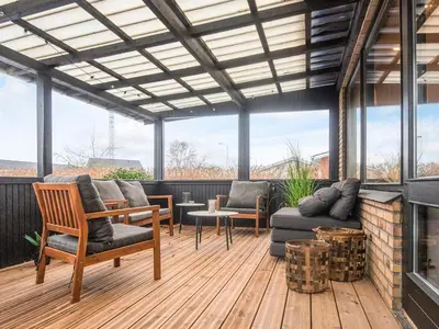 a screened in porch with furniture and a fireplace at 4 star holiday home in Viborg in Viborg