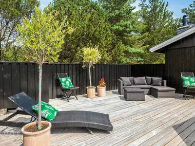 a patio with a couch and chairs on a wooden deck at 4 star holiday home in Blokhus in Blokhus