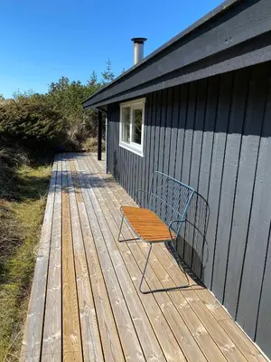a bench sitting on a wooden deck next to a building at Peaceful Base Near Beach And Nature in Saltum