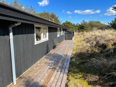 a wooden deck next to a black building at Peaceful Base Near Beach And Nature in Saltum