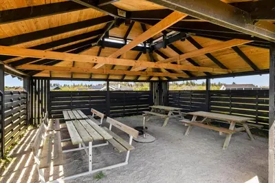 a group of benches sitting under a wooden pavilion at JB405-Brovst-Kronvildtvej-37 in Tranum Strand