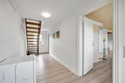 a hallway with white walls and a wooden stair case at Feddet, Jørgen's Feriehus in Lemvig