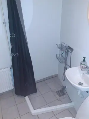 a bathroom with a black shower curtain and a sink at Stor lejlighed ved togstation in Viborg