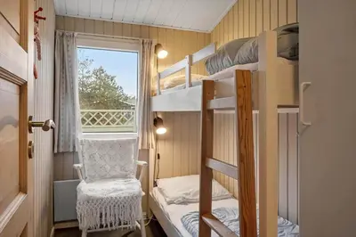 a room with bunk beds with a chair and a window at 1371-Thisted-Havtornvej-1 in Nørre Vorupør