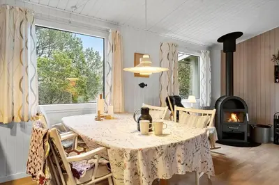 a dining room with a table and a fireplace at 1371-Thisted-Havtornvej-1 in Nørre Vorupør