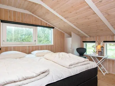 a bedroom with a large bed in a room with wooden walls at 4 star holiday home in Løkken in Løkken