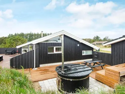a black house with a deck and a picnic table at 4 star holiday home in Løkken in Løkken