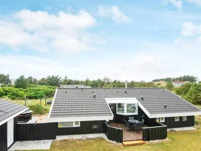 a house with a black roof and a deck at 4 star holiday home in Løkken in Løkken