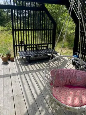 a swing with two pillows and a bench on a porch at Cosy Little Wooden House On Natural Grounds in Vestervig