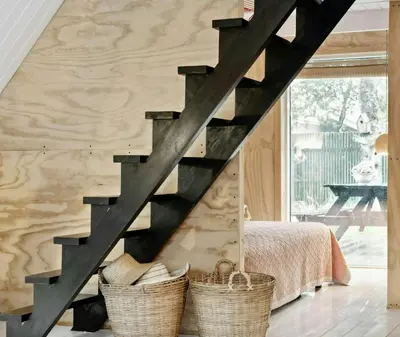 a black staircase in a bedroom with baskets at Cosy Little Wooden House On Natural Grounds in Vestervig