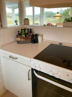 a kitchen with a stove and a basket of bottles at Summer House With Views Over Jammerbugt in Saltum