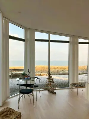 a living room with a table and a view of the ocean at Restored Fisherman's House On Cliff In Thy in Hanstholm