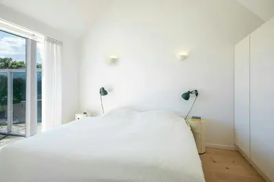 a white bedroom with a bed and a window at Thatched House At First Dune Row In Blokhus in Blokhus