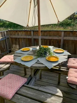 a wooden table with yellow plates and an umbrella at Holiday Home By The North Sea Dunes In Rødhus in Pandrup