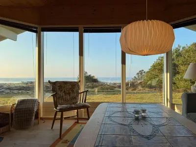 a dining room with a table and views of the ocean at Holiday Home With Private Beach Trail And Sea View in Trend