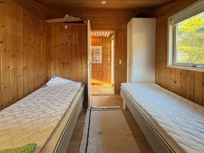 a bedroom with two beds in a wooden cabin at Holiday Home With Private Beach Trail And Sea View in Trend