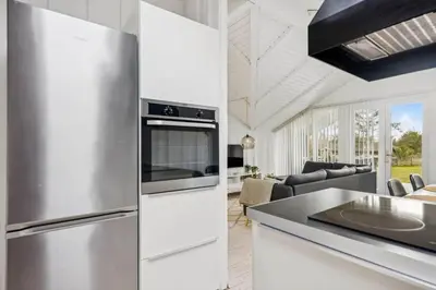 a kitchen with a stainless steel refrigerator and a living room at BL1155-Blokhus-Berberisvej-74 in Blokhus