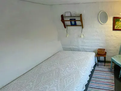 a small bedroom with a white bed and a table at Historic House From 1887 Near Nationalpark Thy