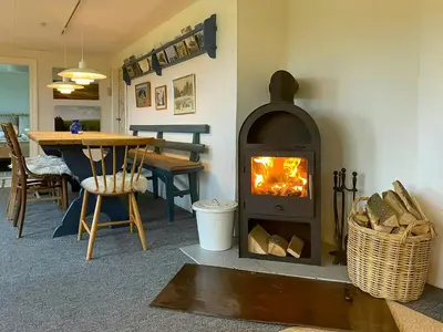 a fireplace in a living room with a table and a dining room at Historic House From 1887 Near Nationalpark Thy