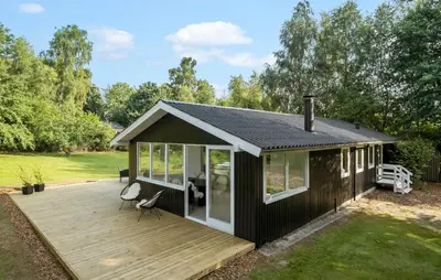 a small black house with a wooden deck at Nice Home In Farsø With House A Panoramic View in Farsø