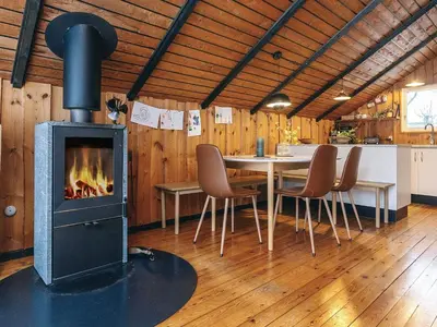 a fireplace in a dining room with a table and chairs at Holiday home near fishing lake in Fjerritslev