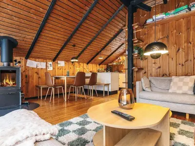 a living room with a table and a fireplace at Holiday home near fishing lake in Fjerritslev