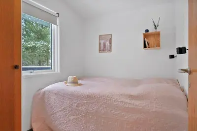 a bedroom with a bed and a window at BL1154-Blokhus-Kornblomstvej-22 in Blokhus