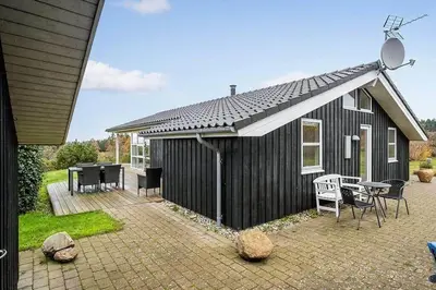 a black house with a patio with a table and chairs at JB406-Fjerritslev-Aspevej-68 in Fjerritslev