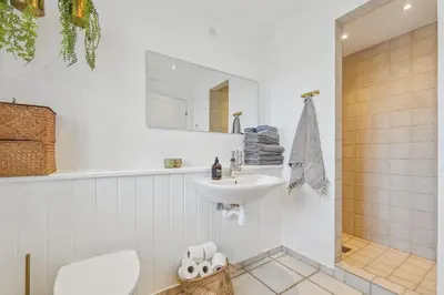 a white bathroom with a sink and a mirror at Holstvej 21 in Blokhus