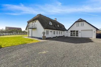 a house with a thatched roof and a driveway at Holstvej 21 in Blokhus