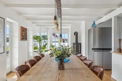 a dining room with a long wooden table and chairs at Holstvej 21 in Blokhus