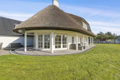 a thatch roofed house with a grass yard at Holstvej 21 in Blokhus
