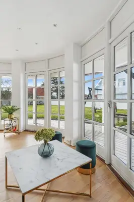 a living room with a table and chairs and windows at Holstvej 21 in Blokhus