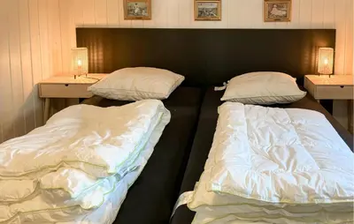 two beds in a room with two night stands at 3 Bedroom Awesome Home In Farsø in Farsø