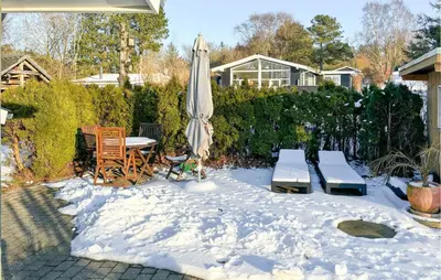 a patio with an umbrella and a table and chairs in the snow at 3 Bedroom Awesome Home In Farsø in Farsø