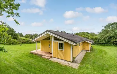 a small yellow building in a field of grass at Holiday Home Hurup Thy With A Fireplace 06 in Heltborg