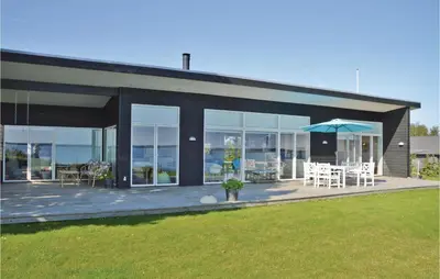 a house with a patio with chairs and an umbrella at Holiday Home Roslev With A Fireplace 01 in Roslev