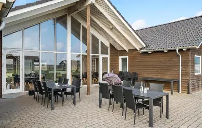 a patio with black tables and chairs and windows at Cozy Home In Harboøre With Kitchen in Harboør