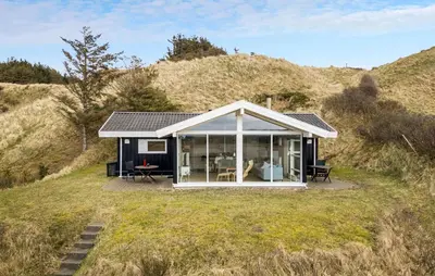 a small house on a hill with glass doors at Holiday Home Blokhus With Fireplace 05 in Blokhus