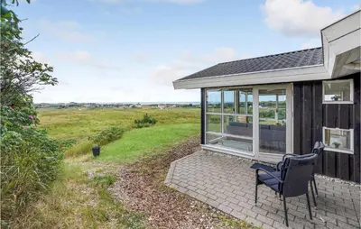 a house with a chair sitting outside of it at Holiday Home Blokhus With Fireplace 05 in Blokhus