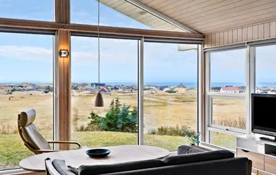 a living room with a table and a large window at Holiday Home Blokhus With Fireplace 05 in Blokhus