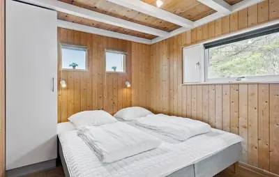 a bedroom with a bed in a wooden wall at Holiday Home Blokhus With Fireplace 05 in Blokhus