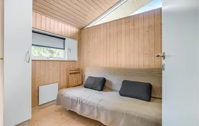 a bedroom with a bed in a room with wooden walls at Holiday Home Blokhus With Fireplace 05 in Blokhus